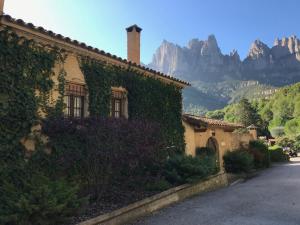 un bâtiment recouvert de lierre avec des montagnes en arrière-plan dans l'établissement Montserrat La Calsina, à Monistrol de Montserrat