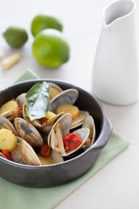 a pan filled with clams and vegetables on a table at Hotel Emporda in Figueres