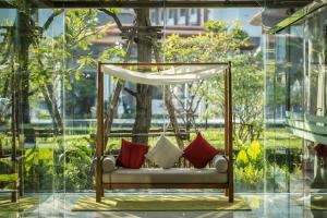 Summit Windmill Golf Suite Hotel at Suvarnabhumi في بانغنا: أرجوحة مع الوسائد في غرفة مع نوافذ