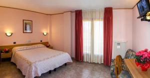 a bedroom with a bed and a window with red curtains at Hotel Les Saisons in Saint Vincent