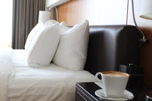 Una cama con almohadas y una taza de café sobre una mesa. en Hotel Arista, en Naperville