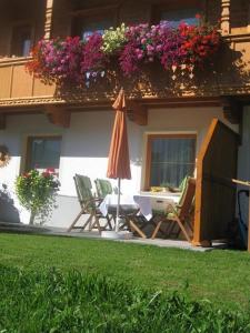 un patio con sillas, sombrilla y flores en Apartment Galtenberg, en Alpbach