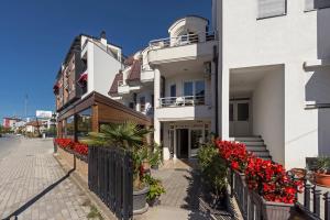 eine Reihe weißer Gebäude mit roten Blumen auf einer Straße in der Unterkunft Villa Veron in Ohrid