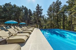 einen Pool mit Liegestühlen und Sonnenschirmen in der Unterkunft SPA Hotel Infinity Park Velingrad in Welingrad