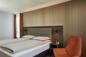 una camera con letto e sedia di H4 Hotel Residenzschloss Bayreuth a Bayreuth