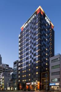 APA Hotel Iidabashi Ekiminami في طوكيو: مبنى عليه علامة فندق هيلتون