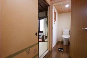 een badkamer met een toilet en een deur naar een kamer bij Hinode Ryokan in Ise