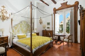 ein Schlafzimmer mit einem Himmelbett und einem Tisch in der Unterkunft Hotel Palazzo Murat in Positano