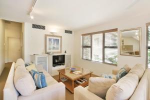 a living room with two white couches and a tv at Tranquil Little Cove Unit, Pool Escape in Noosa Heads