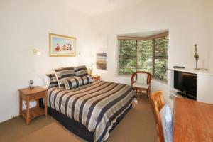 a bedroom with a bed and a desk and a television at Tranquil Little Cove Unit, Pool Escape in Noosa Heads