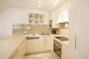 a kitchen with white cabinets and a sink at Tranquil Little Cove Unit, Pool Escape in Noosa Heads