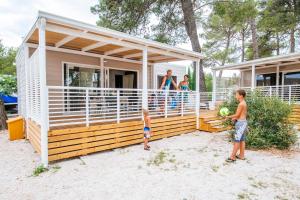 una familia parada en la cubierta de una casa pequeña en Zaton Holiday Resort Mobile Homes, en Nin