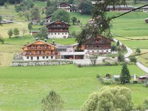 een groot huis op een groene heuvel met een veld bij Huberhof in San Candido