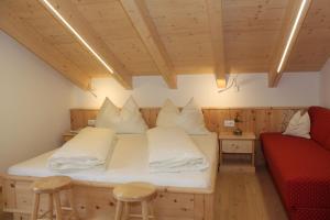 een kamer met een bed met witte kussens en een rode bank bij Huberhof in San Candido