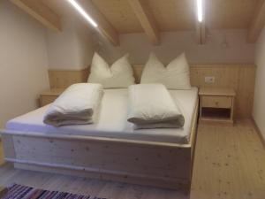 een bed met witte kussens in een kamer bij Huberhof in San Candido