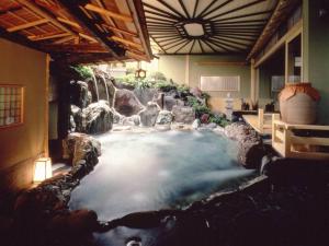 una piscina d'acqua in una stanza con cascata di Itoen Hotel Matsukawakan a Ito