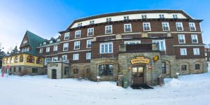 un grand bâtiment en briques dans la neige dans l'établissement Hotel Tanecnica, à Pustevny