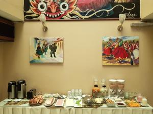 a table with food on it with paintings on the wall at UTASA VILLA REAL inn in Puno