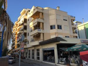 a tall building with a cafe in front of it at Comfortable apartment next to the beach in Durrës