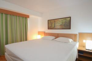 a bedroom with a large white bed with two pillows at Rio Quente Resorts - Hotel Giardino in Rio Quente