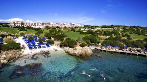 una vista aérea de un complejo con sombrillas azules y agua en COLONNA RESORT, a Colonna Luxury Beach Hotel, Porto Cervo, en Porto Cervo