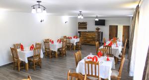 a dining room with white tables and chairs with red bows at Pensiunea Mariana in Ocna Şugatag