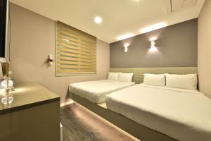 1 dormitorio con 2 camas, escritorio y ventana en With U Hotel & Guesthouse, en Sokcho