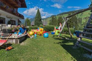 two people sitting on a swing in a yard at Gasthof Tuscherhof in Braies