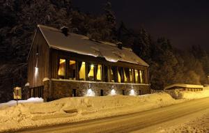 una casa coperta di neve di notte con luci di Krakonošova Dílna "WOODHAUS" a Špindlerův Mlýn