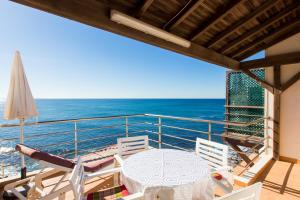 een balkon met een tafel en stoelen en de oceaan bij Casa d'Arriba in Atouguia da Baleia