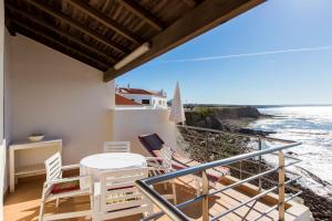 een balkon met een tafel en stoelen en de oceaan bij Casa d'Arriba in Atouguia da Baleia