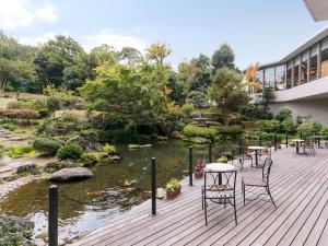 a deck with tables and chairs next to a pond at HOTEL MYSTAYS PREMIER Narita in Narita