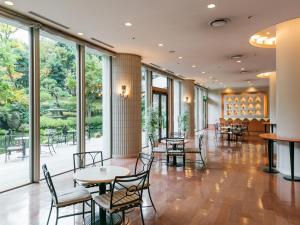 a lobby with tables and chairs and windows at HOTEL MYSTAYS PREMIER Narita in Narita