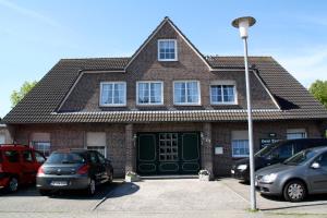 una casa de ladrillo con coches aparcados en un aparcamiento en Haus Daniel, en Neuharlingersiel