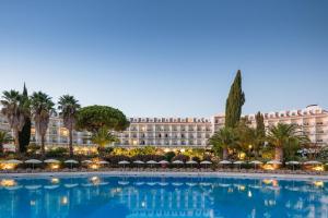 uma grande piscina com guarda-sóis em frente a um grande edifício em Penina Hotel & Golf Resort em Portimão