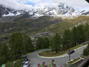 un camino sinuoso en las montañas con coches aparcados en CERVINIA - Appartamento direttamente sulle piste, vista unica sul Cervino, en Breuil-Cervinia