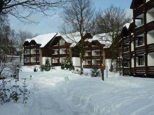 un patio cubierto de nieve frente a dos edificios en Hapimag Ferienwohnungen Braunlage, en Braunlage