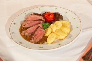 ein Teller mit Fleisch und Kartoffeln auf dem Tisch in der Unterkunft Alpenhof Annaberg in Annaberg im Lammertal