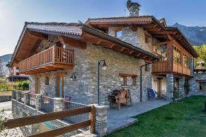 ein Steinhaus mit einem Holzbalkon darauf in der Unterkunft Hotel Lo Campagnar in Courmayeur