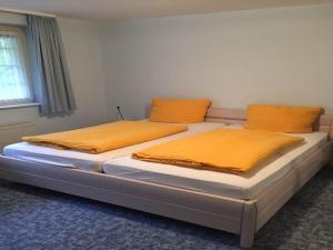 2 camas con almohadas naranjas en una habitación en Hotel Carlsruh, en Braunlage