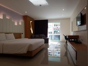 una camera con letto, scrivania e TV di The Whisper Hotel a Centro di Pattaya