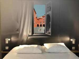 a bed with two pillows in a room with a window at B&B HOTEL Montauban in Montauban