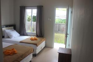 two beds in a room with a window at Adi Bali Homestay in Uluwatu