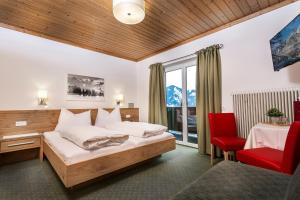 - une chambre avec un lit et une chaise rouge dans l'établissement Pension Margarete, à Zell am See