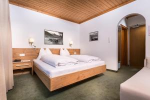 - une chambre avec un grand lit et une tête de lit en bois dans l'établissement Pension Margarete, à Zell am See