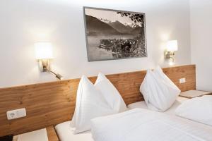 - une chambre avec un lit doté de draps et d'oreillers blancs dans l'établissement Pension Margarete, à Zell am See