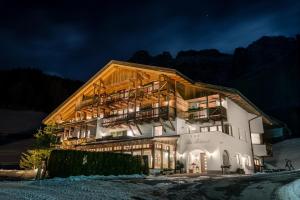 um grande edifício à noite com as luzes acesas em Hotel Ciasa Rü Blanch em San Cassiano