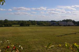 een groot veld met een huis in de verte bij Ty Nant Cottages and Suites in Carterton