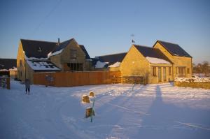 een man die in de sneeuw voor een gebouw staat bij Ty Nant Cottages and Suites in Carterton