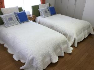 two beds with white blankets and blue pillows in a room at La Curación in Naoshima